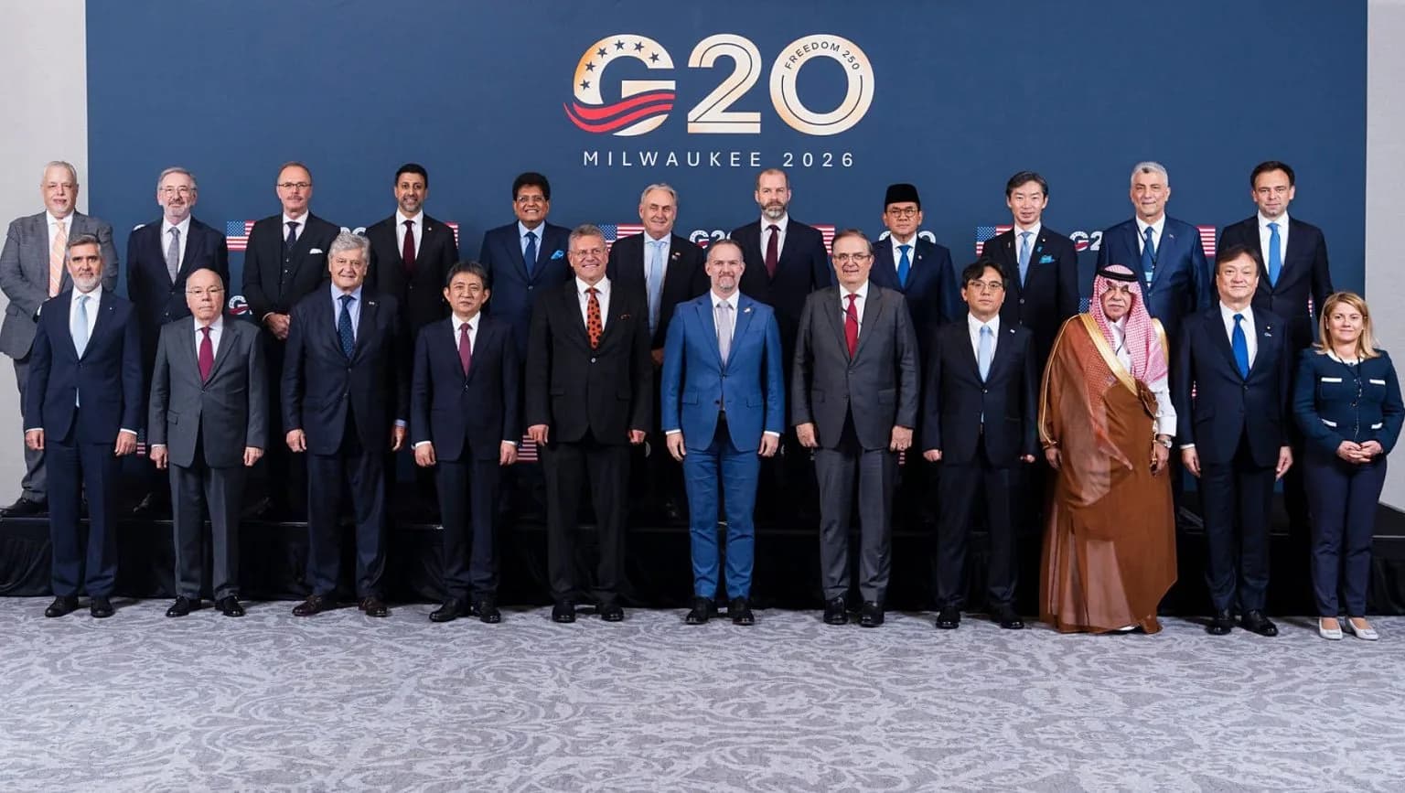 A group of leaders pose for a photo in front of a G20 logo.
