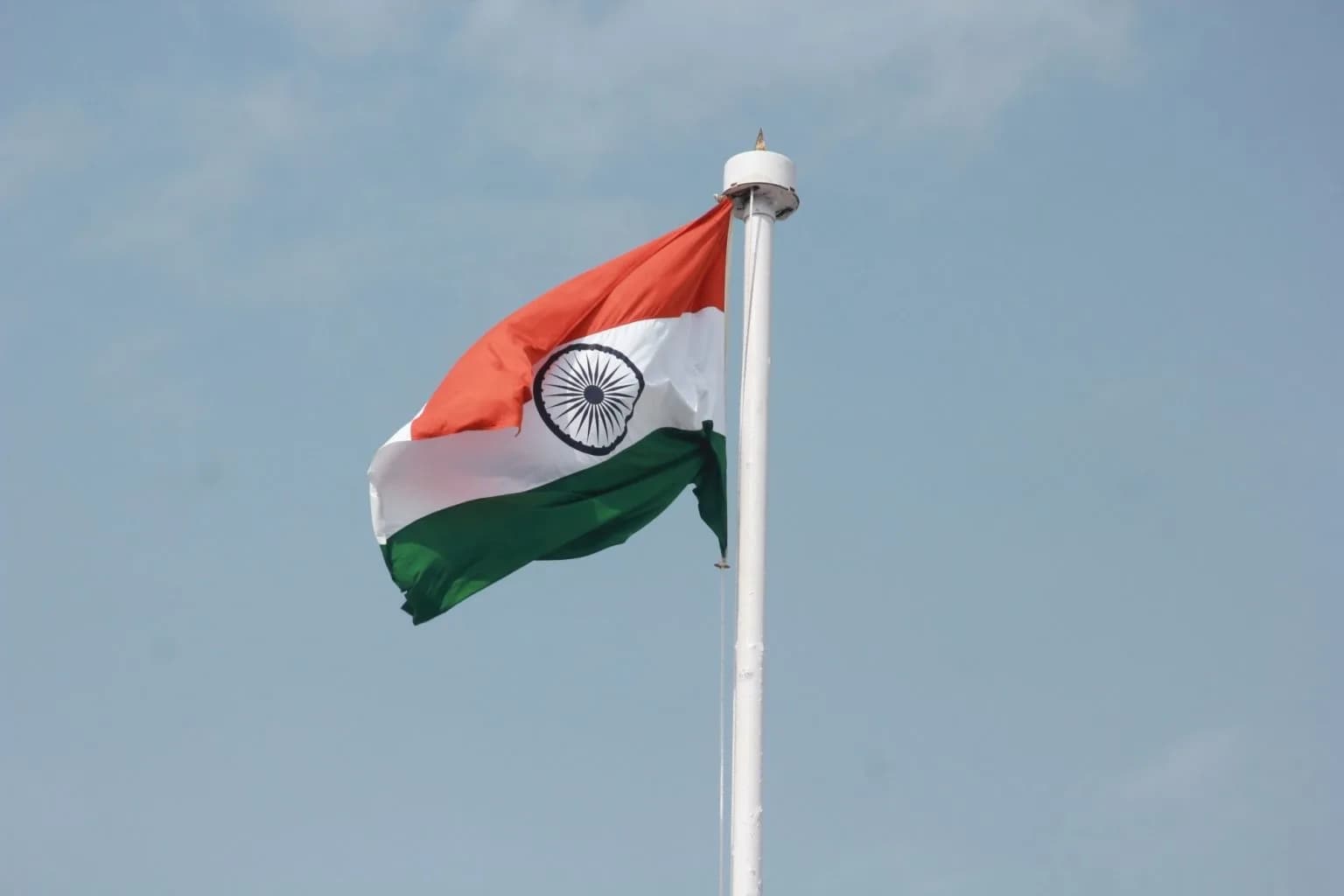 The Indian flag waves against a clear blue sky.