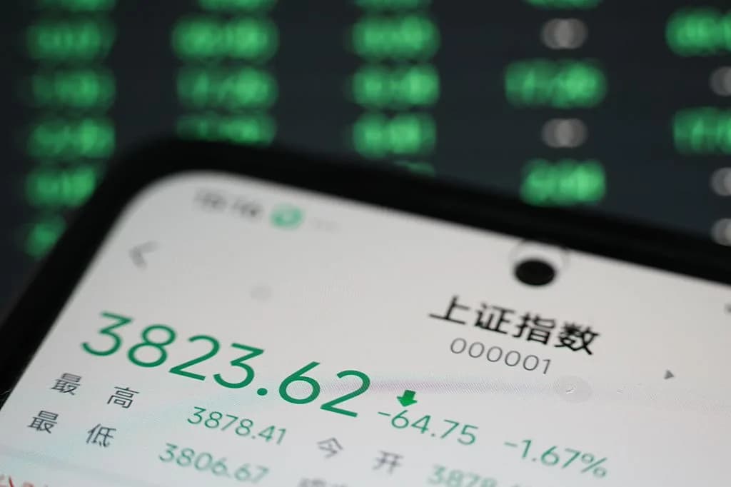 A smartphone displays stock market data with a green downward trend.