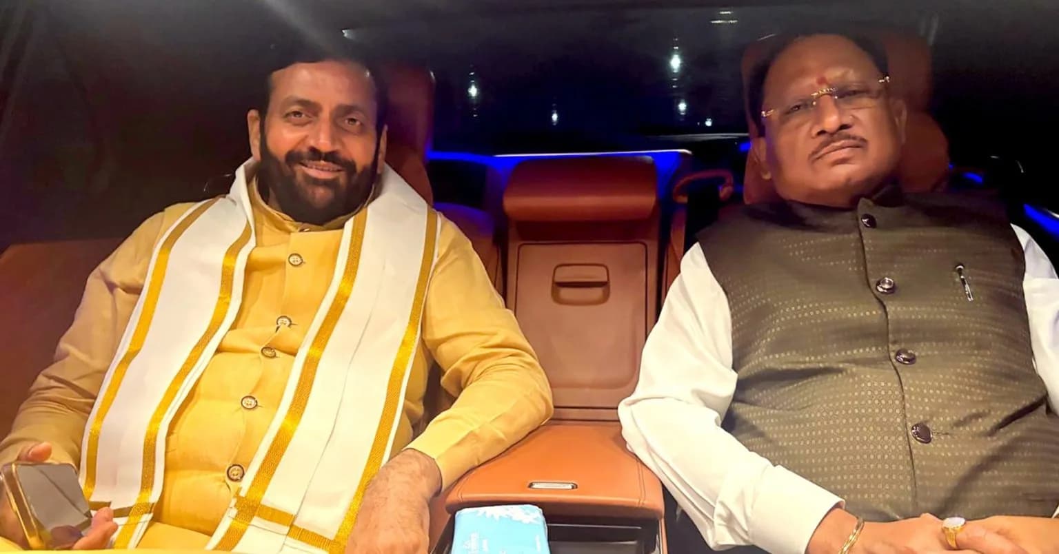 Two men in traditional Indian attire sitting in a car.