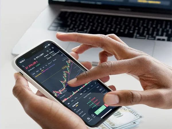 A person's hands holding a smartphone displaying a cryptocurrency trading chart.