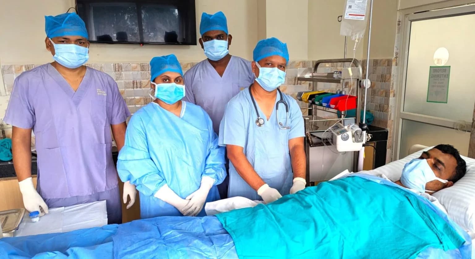 Medical team stands over a patient in a hospital room.