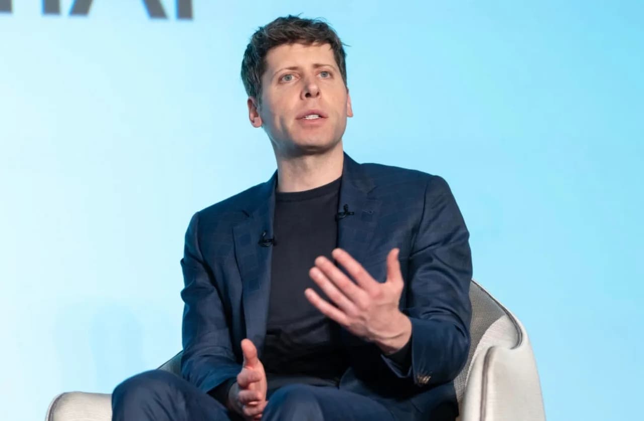 A man in a suit speaks with his hands raised.