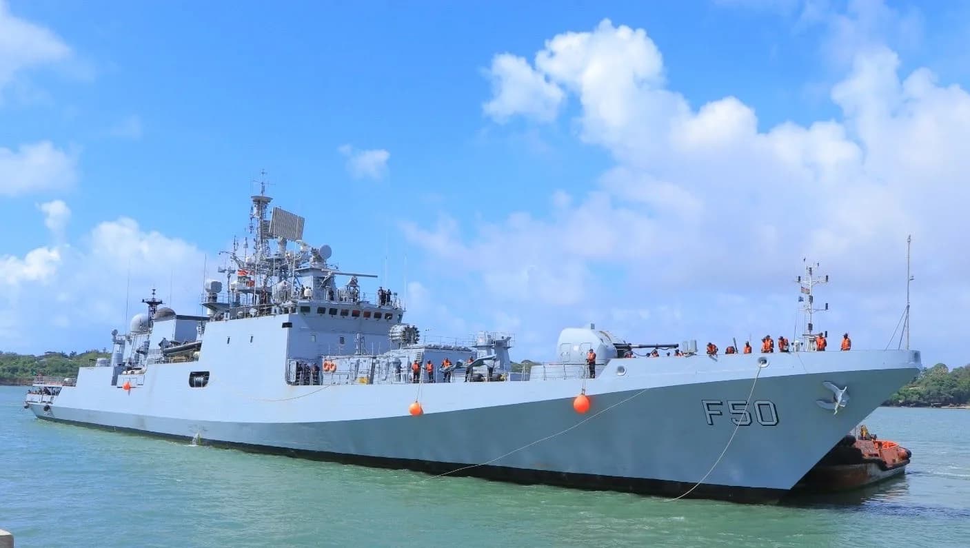 A grey naval ship with F50 on its bow sails on the sea.